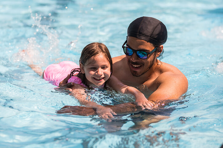 swim instructor helping a small girl learn to swim